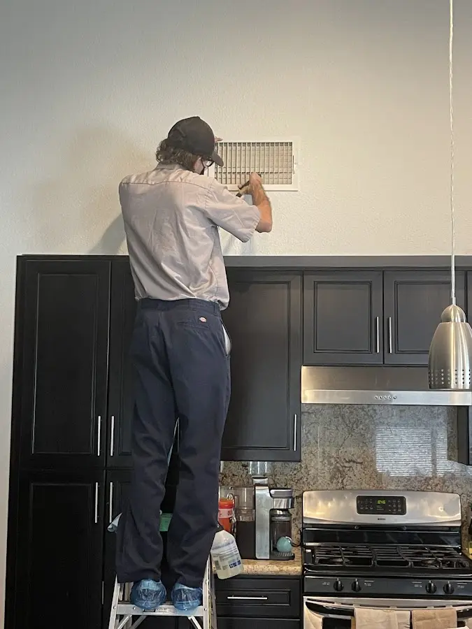 Technician inspecting an air vent during HVAC service in Volo